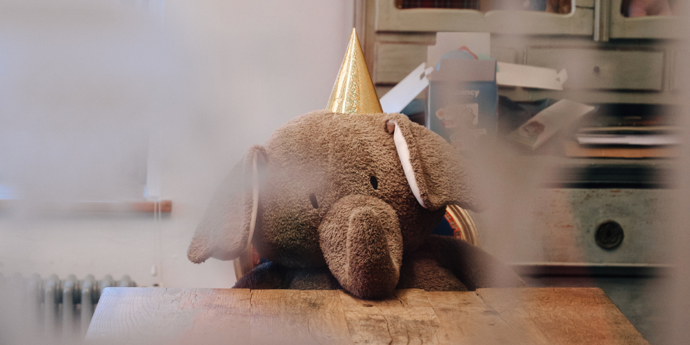 Ein Plüschtier Elefant sitzt mit einem Partyhut an einem Tisch