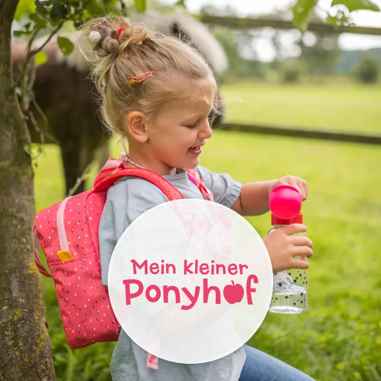 Mädchen im Kindergartenalter steht vor einem Pony und öffnet ihre pinke Trinkflasche